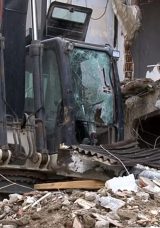 Yıkım sırasında kopan par&ccedil;alar kep&ccedil;enin &uuml;zerine d&uuml;şt&uuml;: Operat&ouml;r&uuml;n bacağı kırıldı